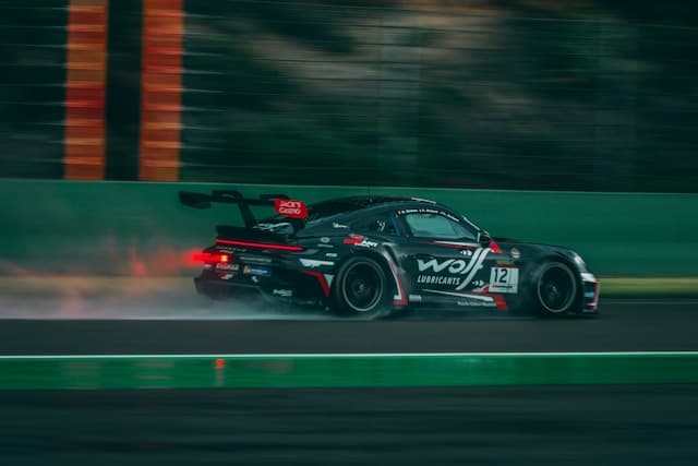 A race car in motion on a wet track at night